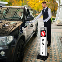 Valet parking attendant assisting a customer with a black SUV, with a valet sign in the foreground.