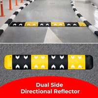 Dual-side directional reflector with black and yellow pattern on a road surface.