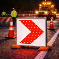 Roadwork scene with a illuminated traffic sign and construction vehicles at night.