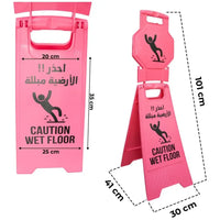 Pink 'Caution Wet Floor' sign with Arabic text and dimensions