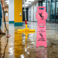 Person cleaning a wet floor with a yellow mop, wearing blue jeans and brown shoes, next to a pink 'Caution Wet Floor' sign.