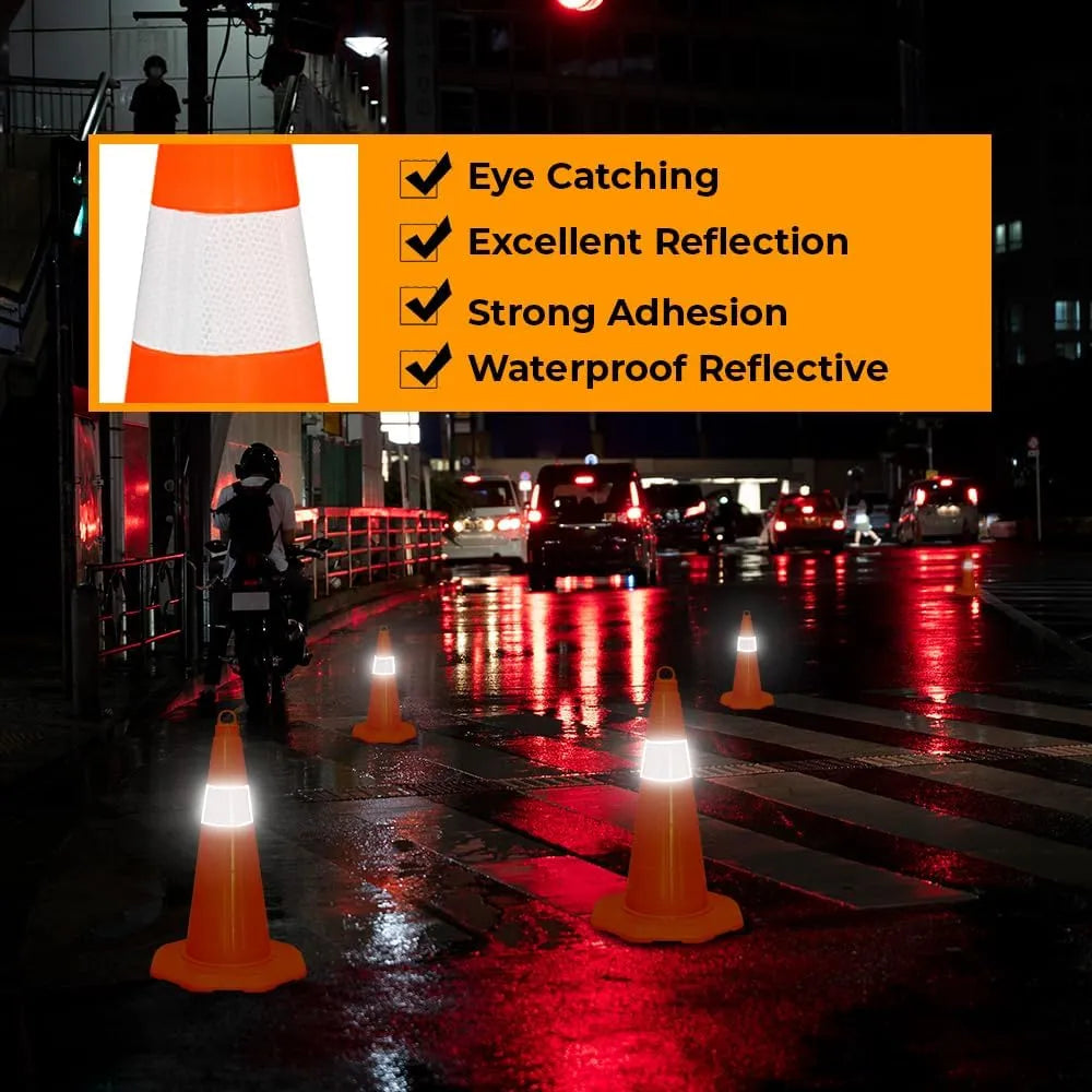 Orange traffic cones on a wet road at night with reflective bands.