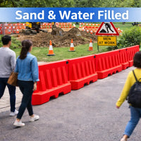 People walking past red barriers with a construction site 