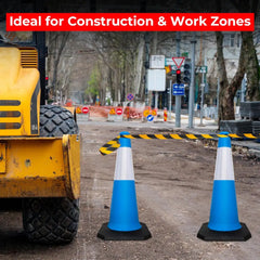 Blue traffic cones on a construction site with a bulldozer and warning signs in the background.