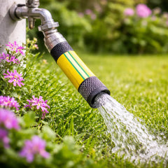 Garden hose nozzle spraying water onto grass with flowers in the background