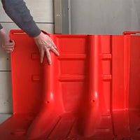 Person interacting with a large red plastic flood barrier in an indoor setting