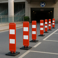 Row of orange traffic barriers with white reflective stripes on a road.
