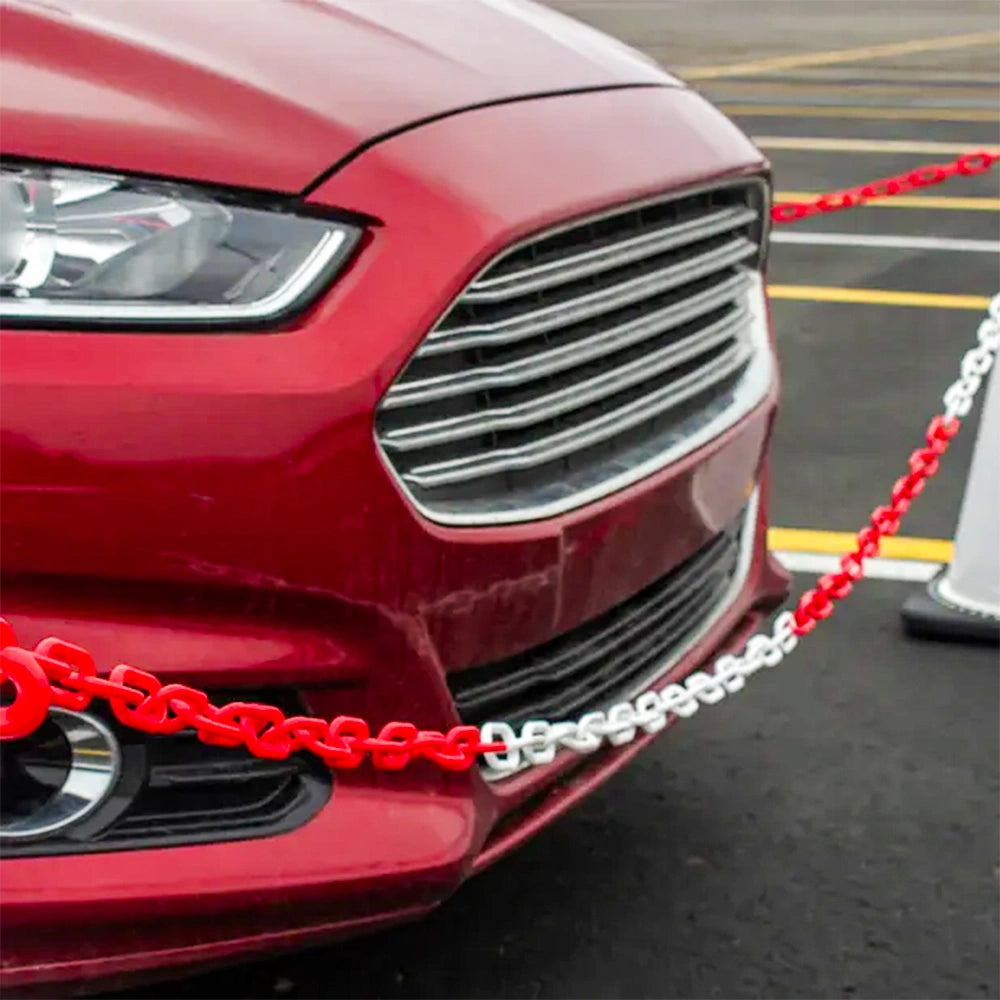 Red car with a plastic barrier chain to its front, on a road.