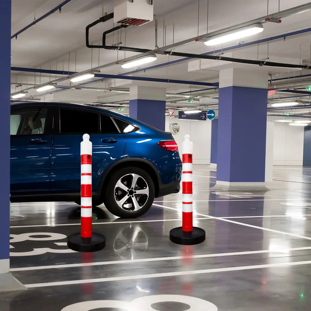 Blue car in a parking garage with traffic cones and visible floor markings.