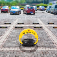 Yellow 'No Parking' sign on a brick pavement with cars in the background