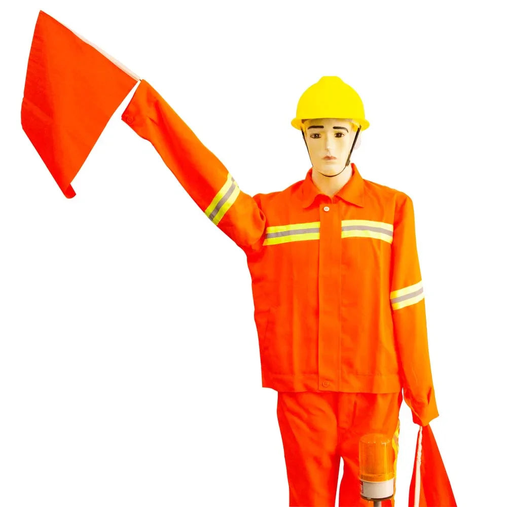 Mannequin wearing an orange safety suit with reflective stripes and a yellow helmet, holding a red flag.