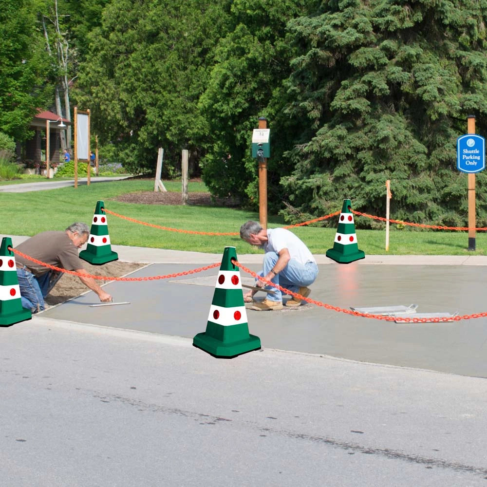 Workers smoothing wet concrete on a road with green and white traffic cones 